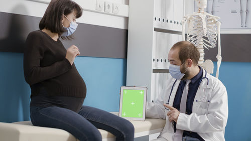 Female doctor discussing with pregnant woman in hospital
