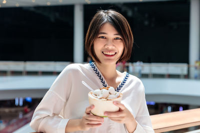 Coconut ice cream in coconut shell in woman hands enjoying eating, thailand street food