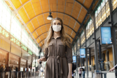 Low angle view of woman wearing mask standing at railroad station