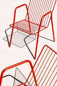 Summer outdoor red metal chairs placed on white floor in sunlight with shadow