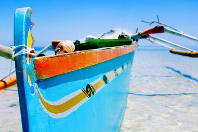 Blue outrigger moored in sea against clear sky