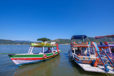 Boat moored in sea against clear blue sky