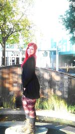 Portrait of smiling young woman standing against built structure