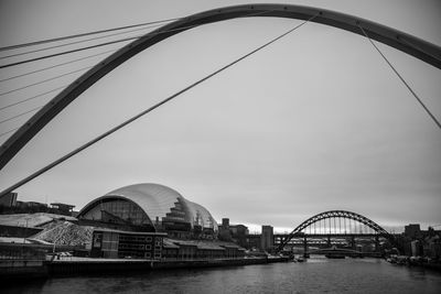 Bridge over river in city against sky