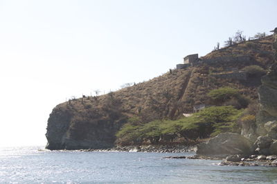 Scenic view of sea and cliff against clear sky