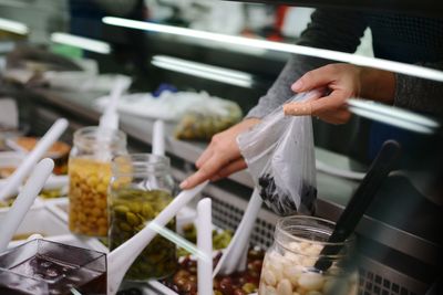 Cropped hand of person packing food in plastic bag at store