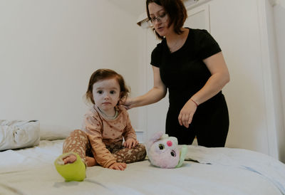 Mom brushes her baby daughter with a cast on her leg.