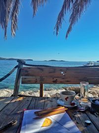 Table by sea against clear blue sky