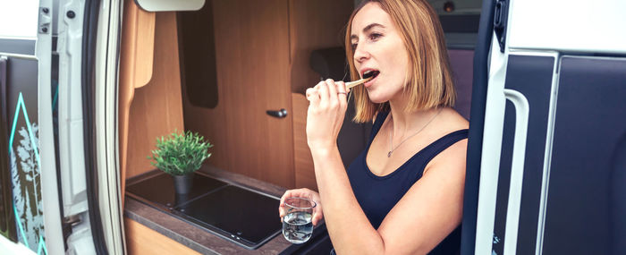 Woman brushing her teeth outdoors during a camper van trip