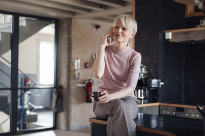 Young woman using phone while sitting on seat