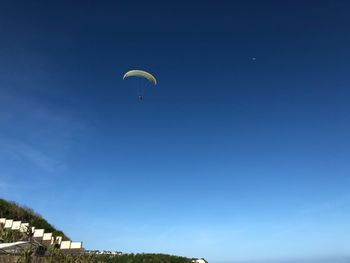 Low angle view of person paragliding against clear blue sky