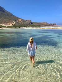 Rear view of woman standing at beach