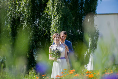 Bride and groom seen through plants at park
