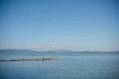 Scenic view of lake trasimeno against blue sky