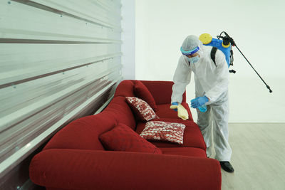 Rear view of man standing on sofa