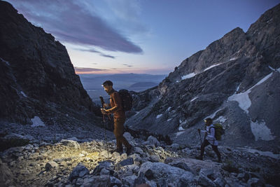 Hikers walk with headlamps at sunrise in grand teton national park