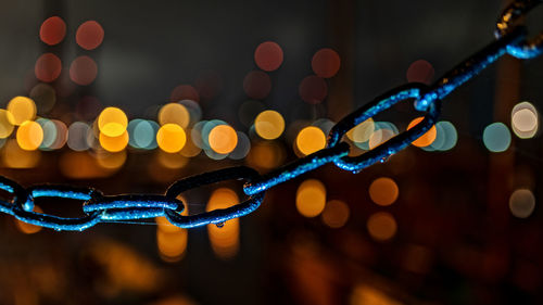 Close-up of chain against illuminated lights at night