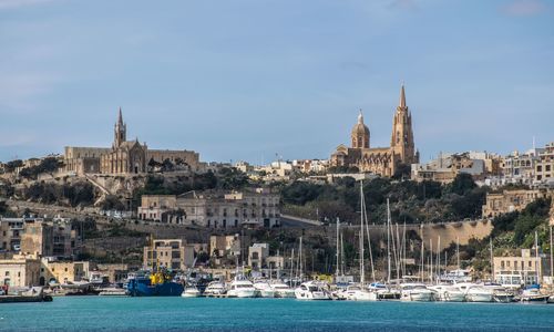 Sailboats in sea with buildings in background