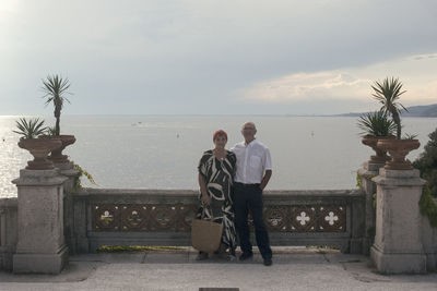 People at observation point by sea against sky