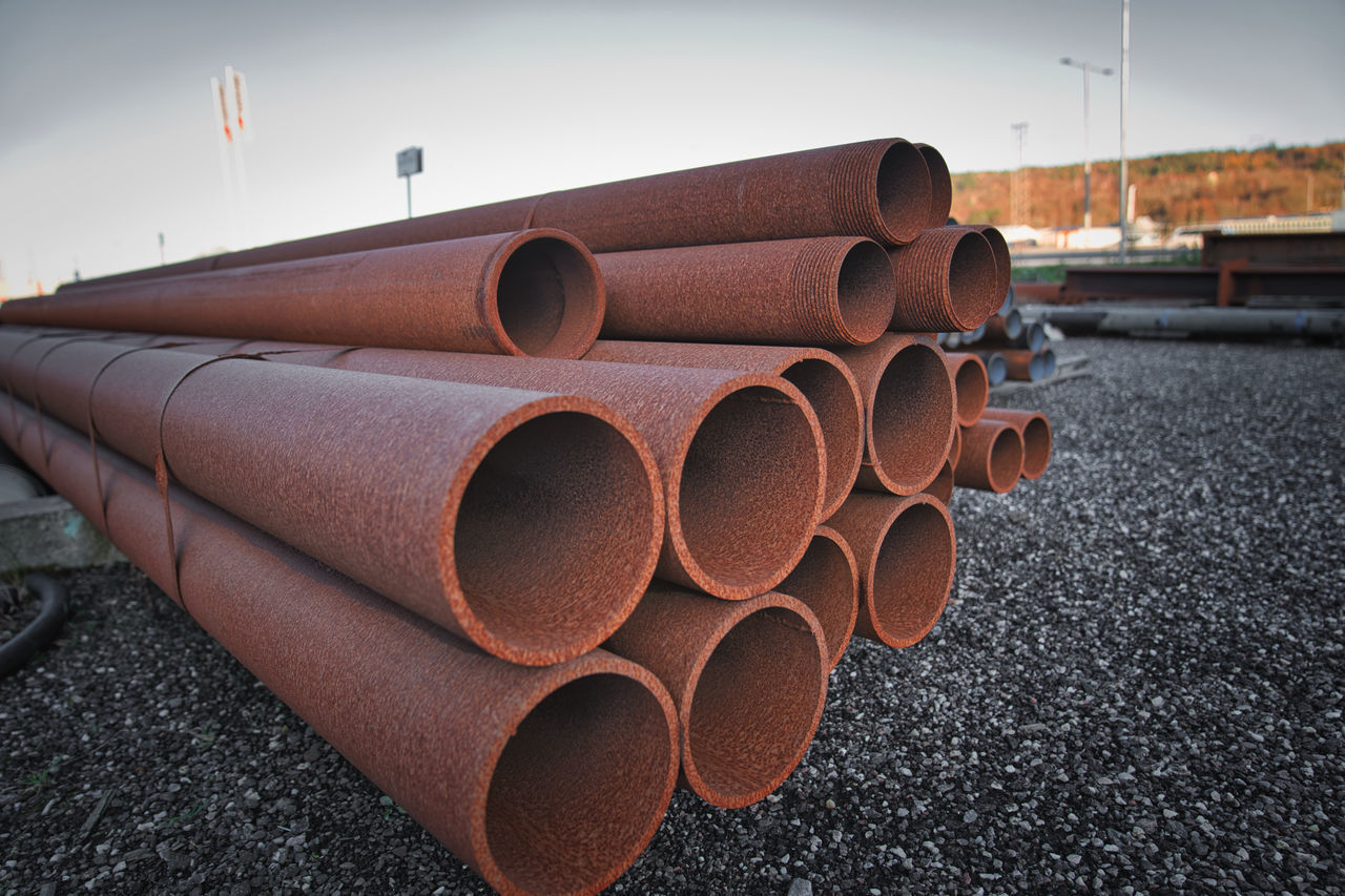 CLOSE-UP OF STACK OF PIPES ON FIELD