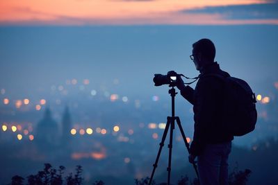 Photographer photographing cityscape through camera during sunset