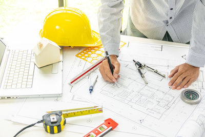 Midsection of architect preparing blueprint at desk