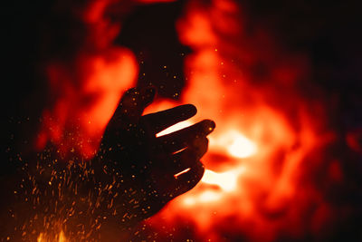 Close-up of hand holding bonfire at night