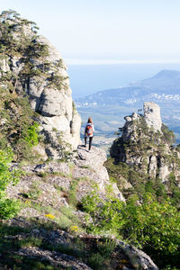 Man on rock by mountains against sky