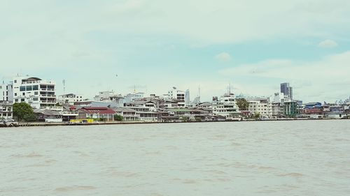 View of cityscape by sea against sky