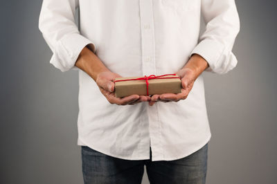 Midsection of man holding hands against white background