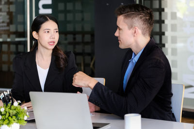 Portrait of smiling businesswoman using laptop while standing in office