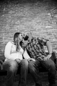 Portrait of smiling young couple on brick wall