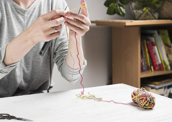 Midsection of woman crocheting at home