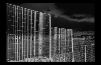 Metal fence by building against sky