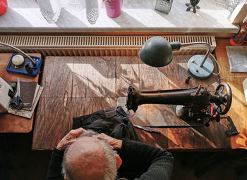 Old tailor in his workshop, sewing, sewing machine, overhead, high angle view.