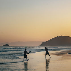 Silhouette people on beach against clear sky