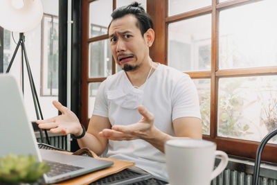 Young man using mobile phone while sitting on table