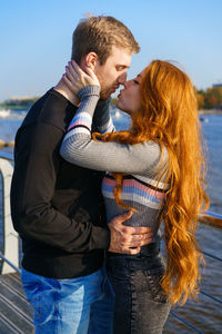 Young couple is standing on the river bank hugging