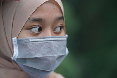 Close-up of woman wearing mask looking away while standing outdoors