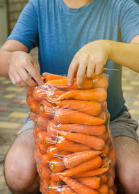 A farmer is packing freshly picked carrots into bags for sale. freshly harvested carrots. 