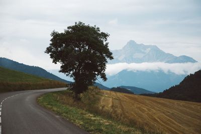 Scenic view of road by mountains against sky