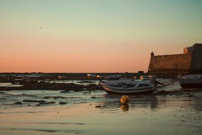 Boats moored on sea against clear sky during sunset