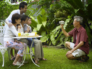 Senior man photographing family at back yard