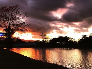 Scenic view of lake against cloudy sky during sunset