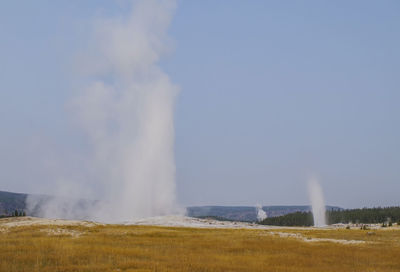 Steam emitting from volcanic landscape against clear sky