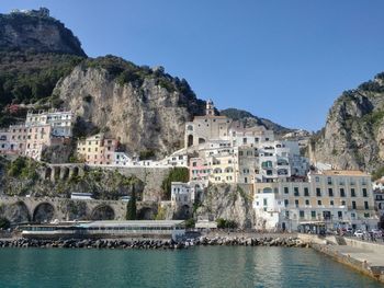 Buildings by sea against clear blue sky