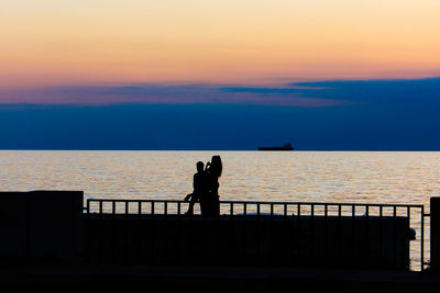 Silhouette people against sea during sunset