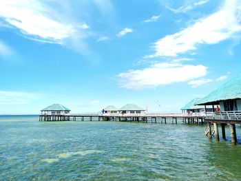 Stilt houses over sea against blue sky