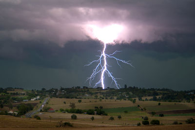 Lightning over landscape against sky at night