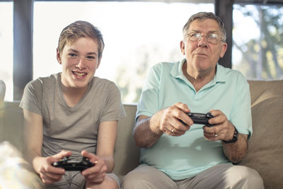 Grandfather and grandson playing video game on couch at home